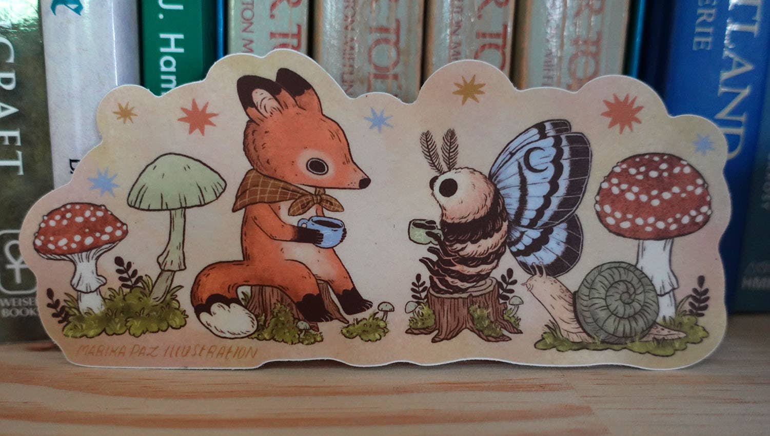 Wooden cutout of a fox and butterfly with mushrooms and flowers on a wooden surface.