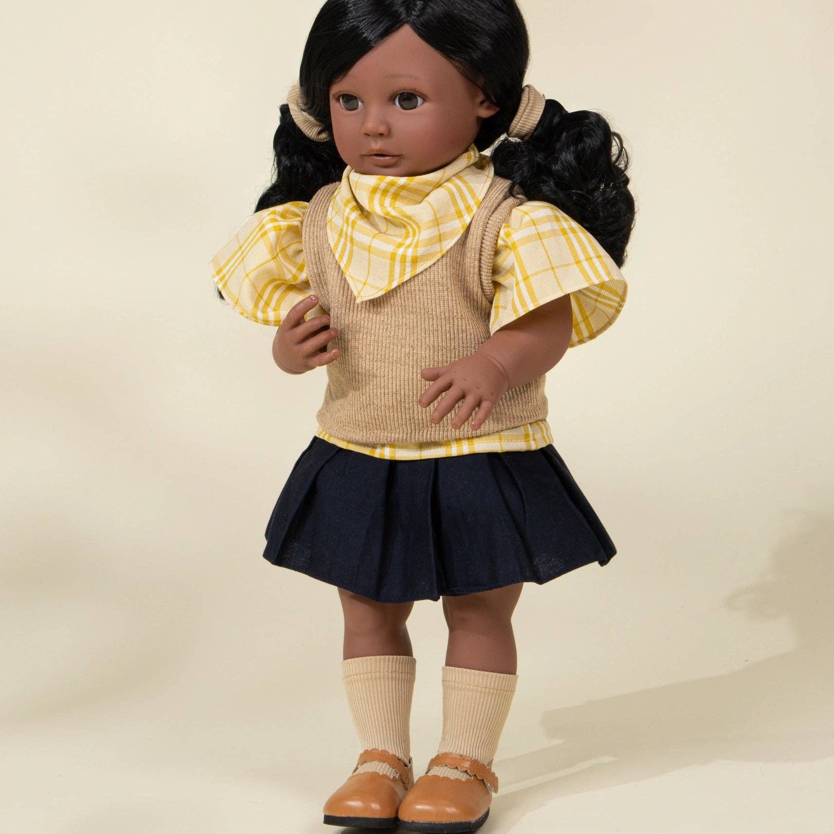 Doll wearing a yellow blouse, beige vest, and navy skirt on a beige background