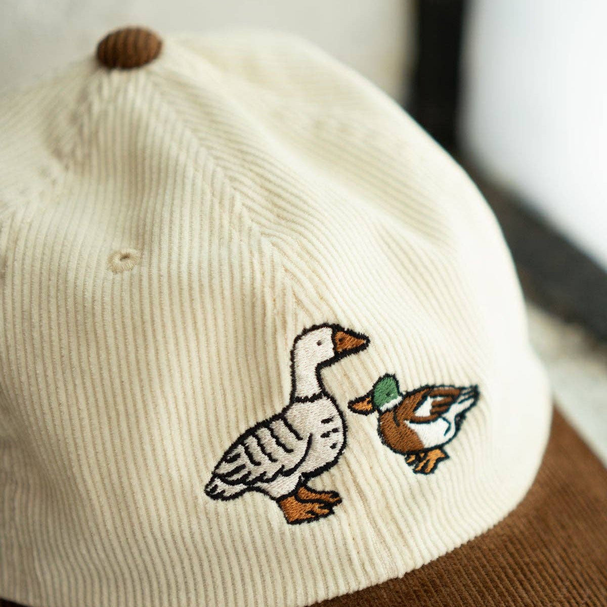 Baseball cap with embroidered ducks on a neutral background