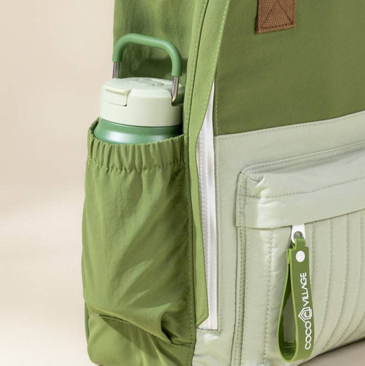 Green backpack with a water bottle in a pocket on a beige background