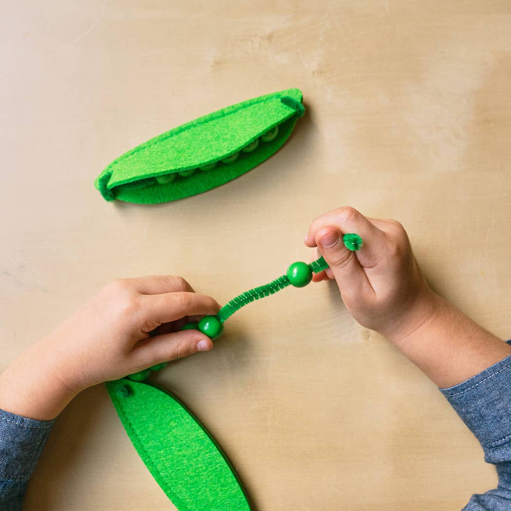 Child's hands playing with a green toy on a beige surface