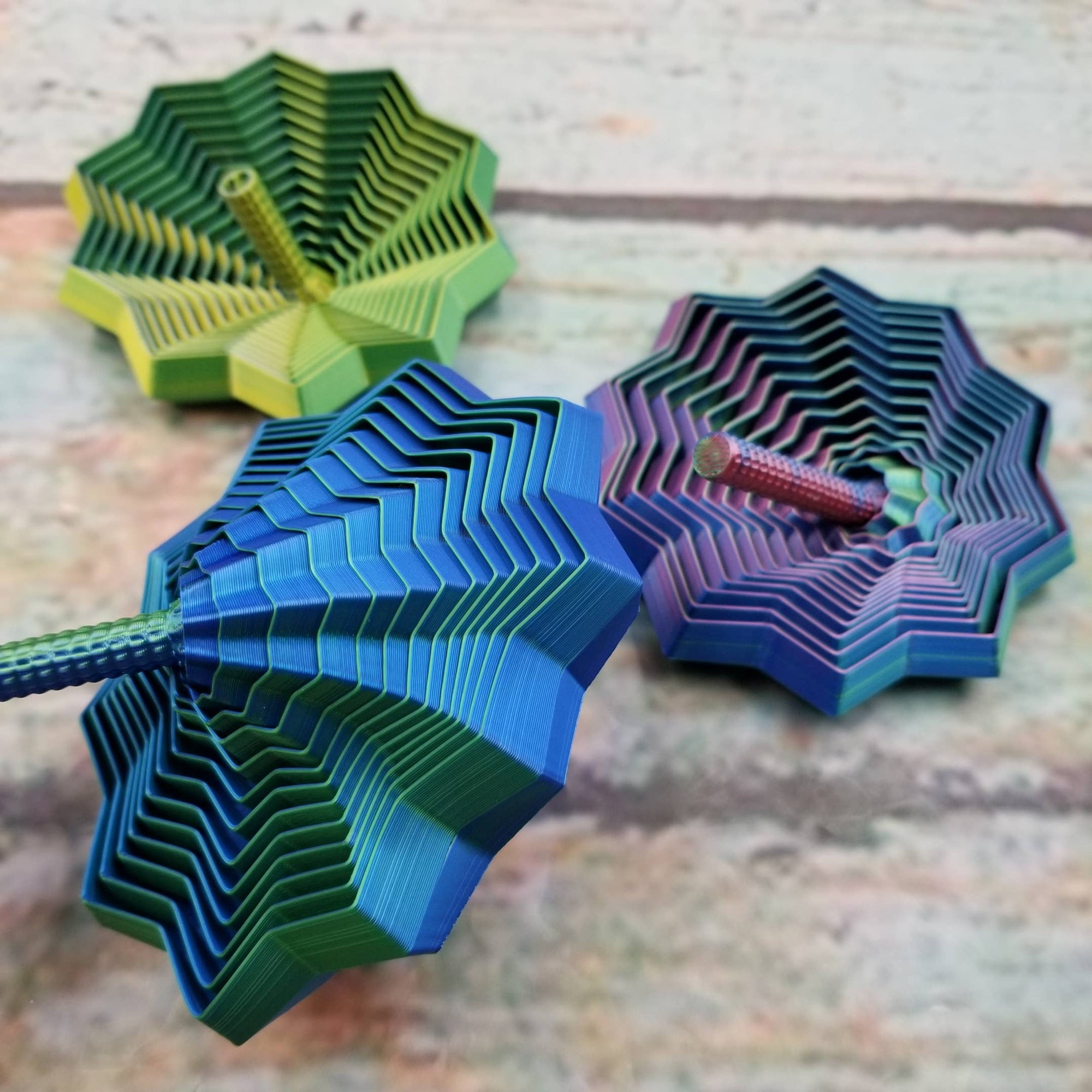 Three colorful paper spiders on a wooden surface