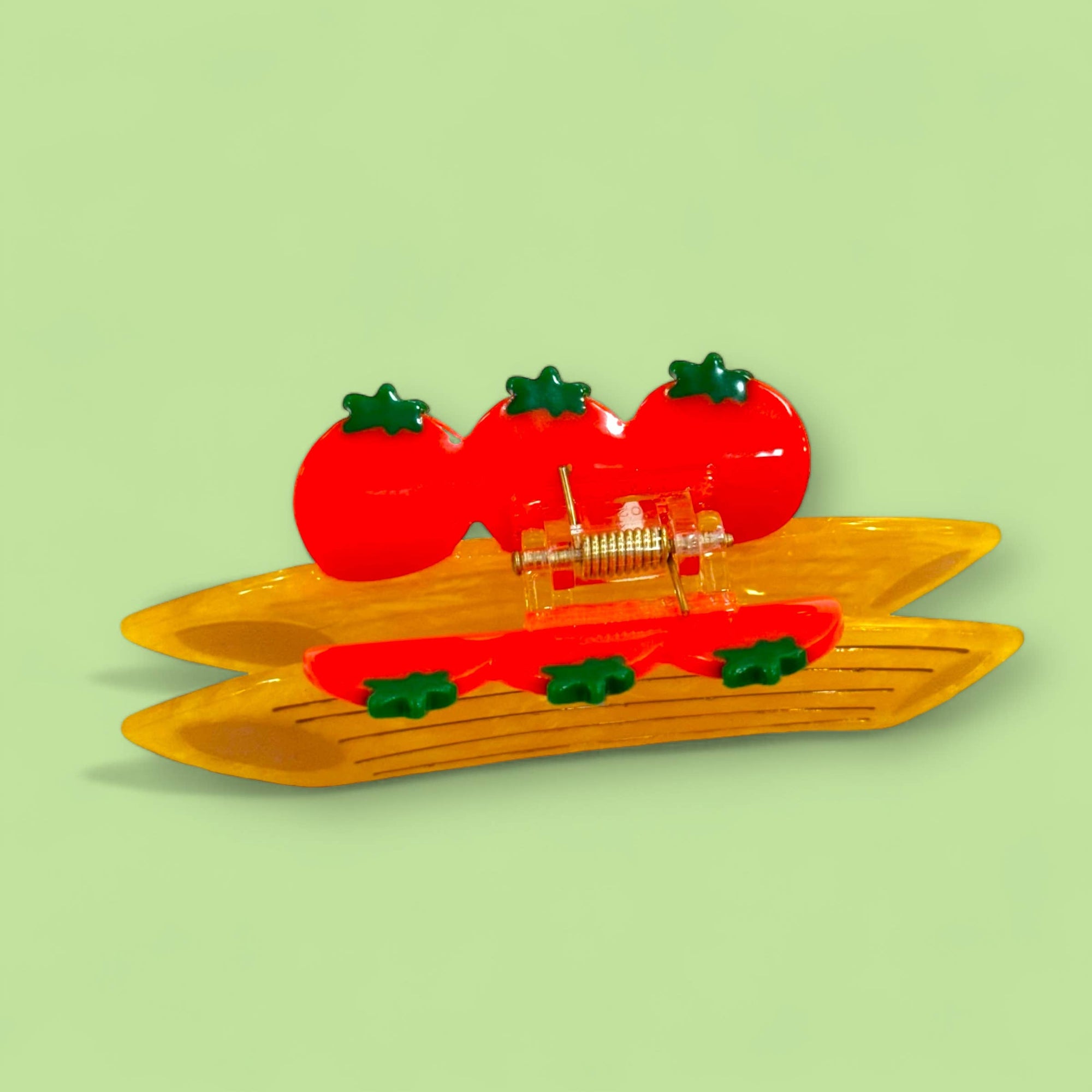Decorative hair clip with tomato design on a light green background