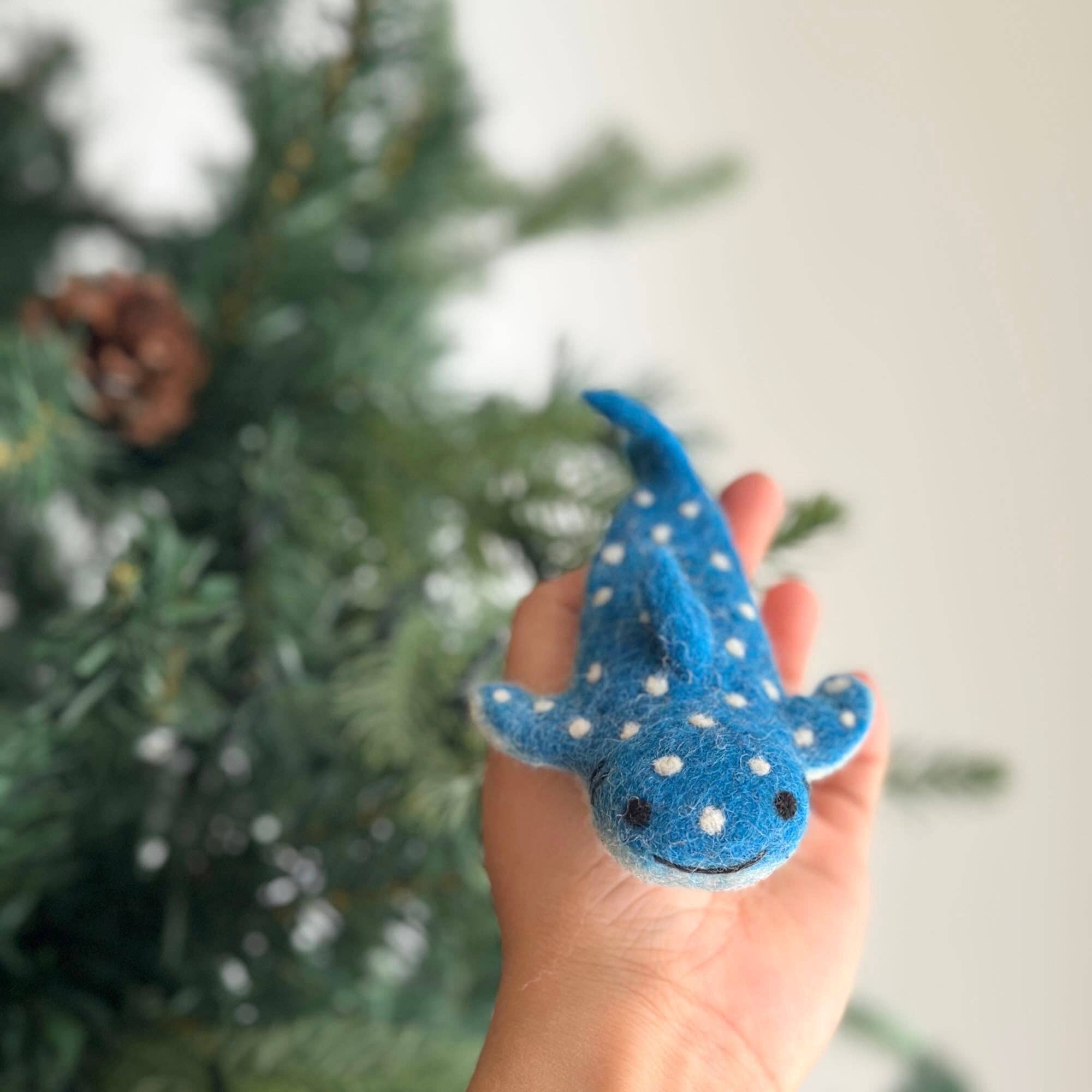 Hand holding a blue and white polka dot toy with a blurred tree in the background