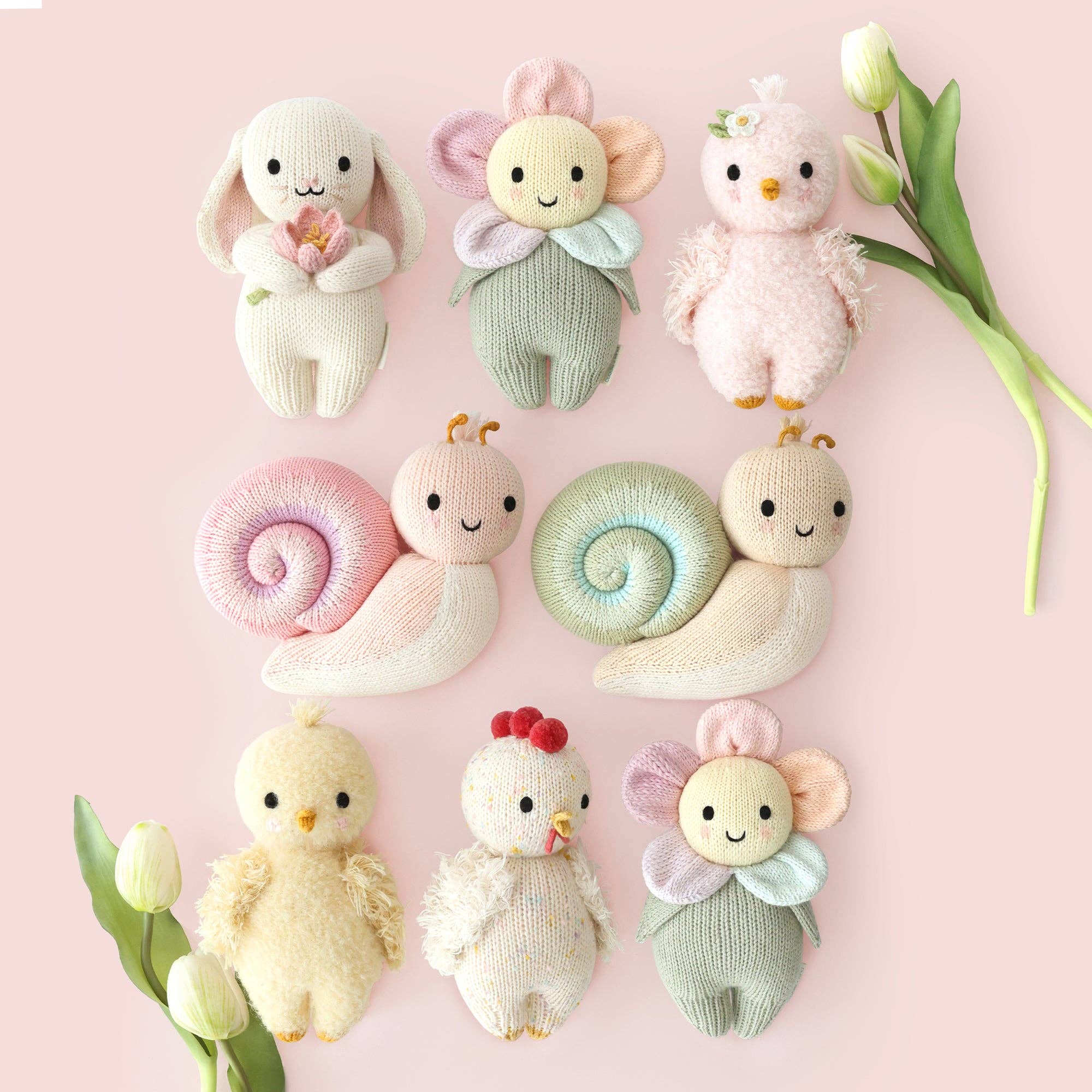Set of cute plush toys on a pink background with tulips