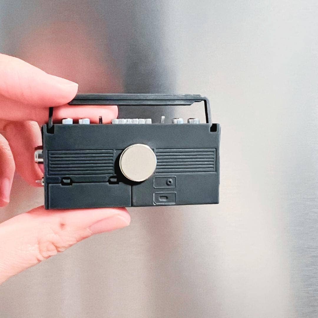Small electronic device held in a hand against a neutral background