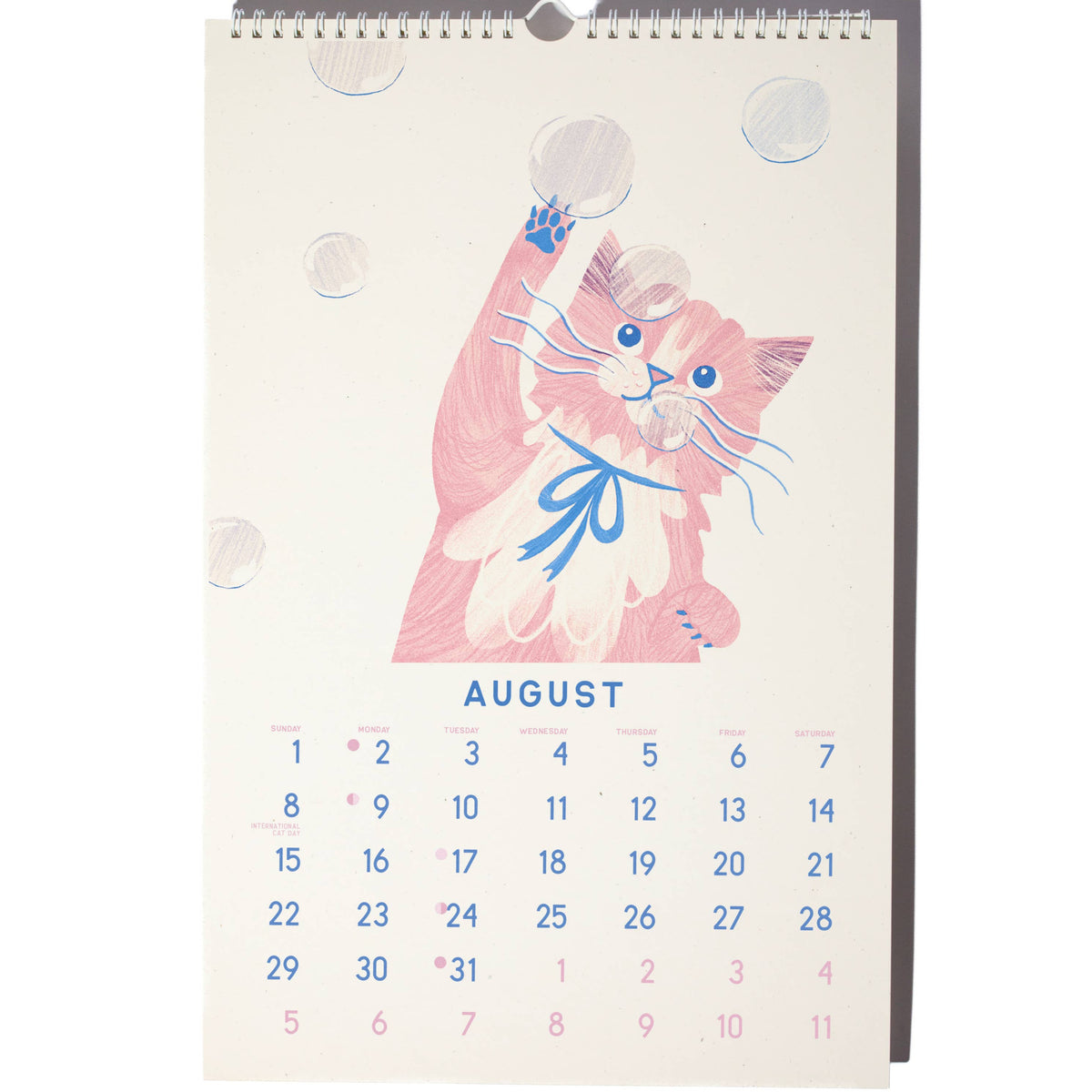 A spiral-bound desk calendar page featuring a pink cartoon cat illustration with a blue bow and the word AUGUST above a numbered calendar grid, shown on a white background.