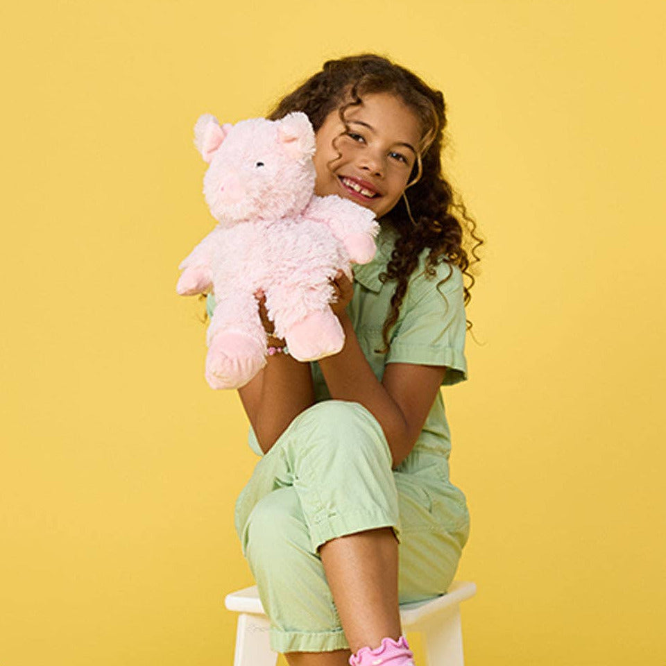 Young girl holding a pink teddy bear against a yellow background