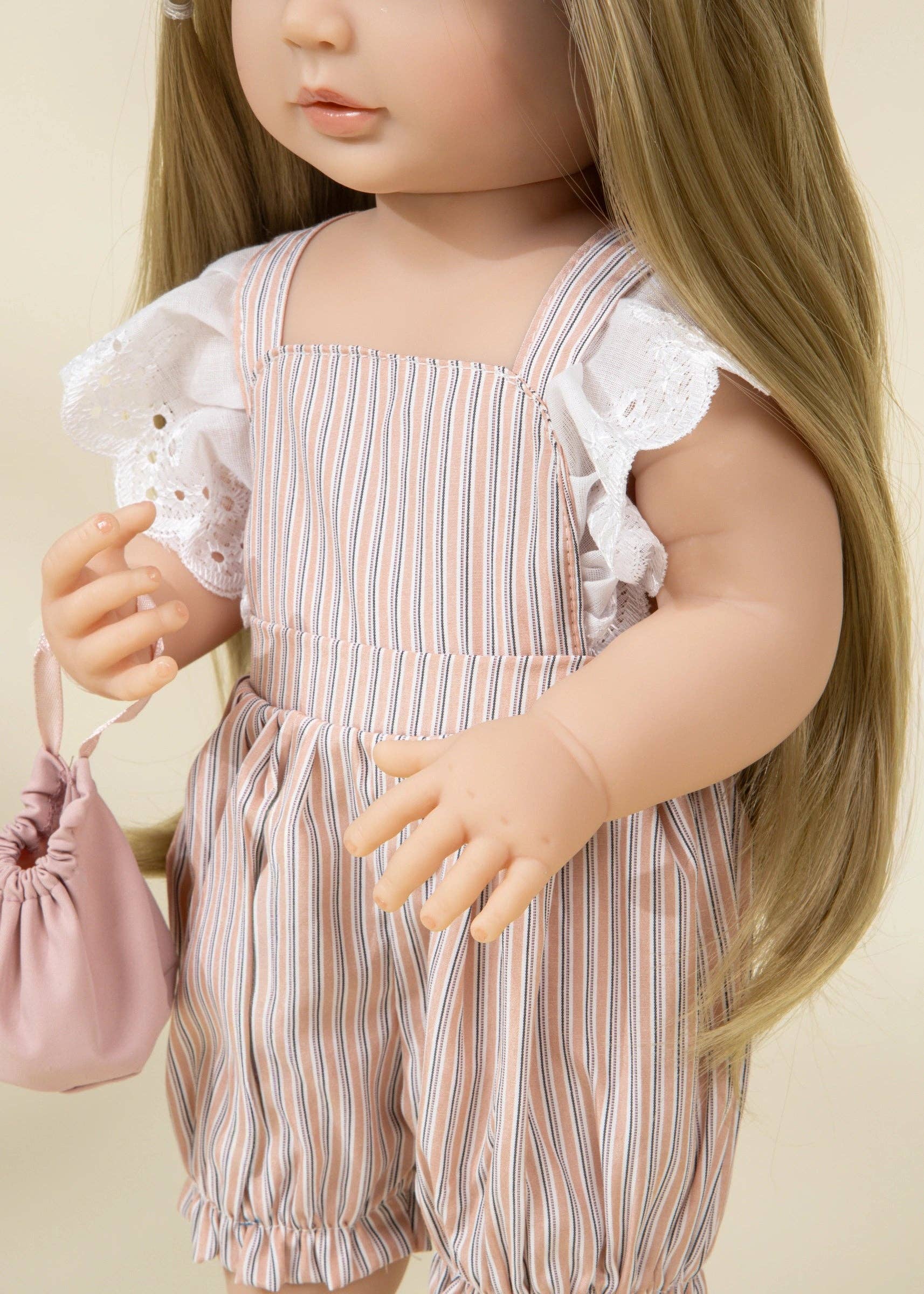 Doll wearing a striped outfit with ruffled sleeves against a beige background