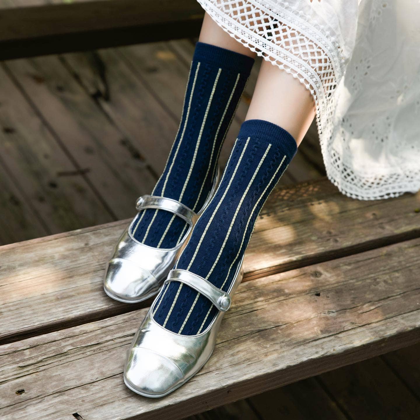 Person wearing navy striped socks and silver shoes on a wooden surface