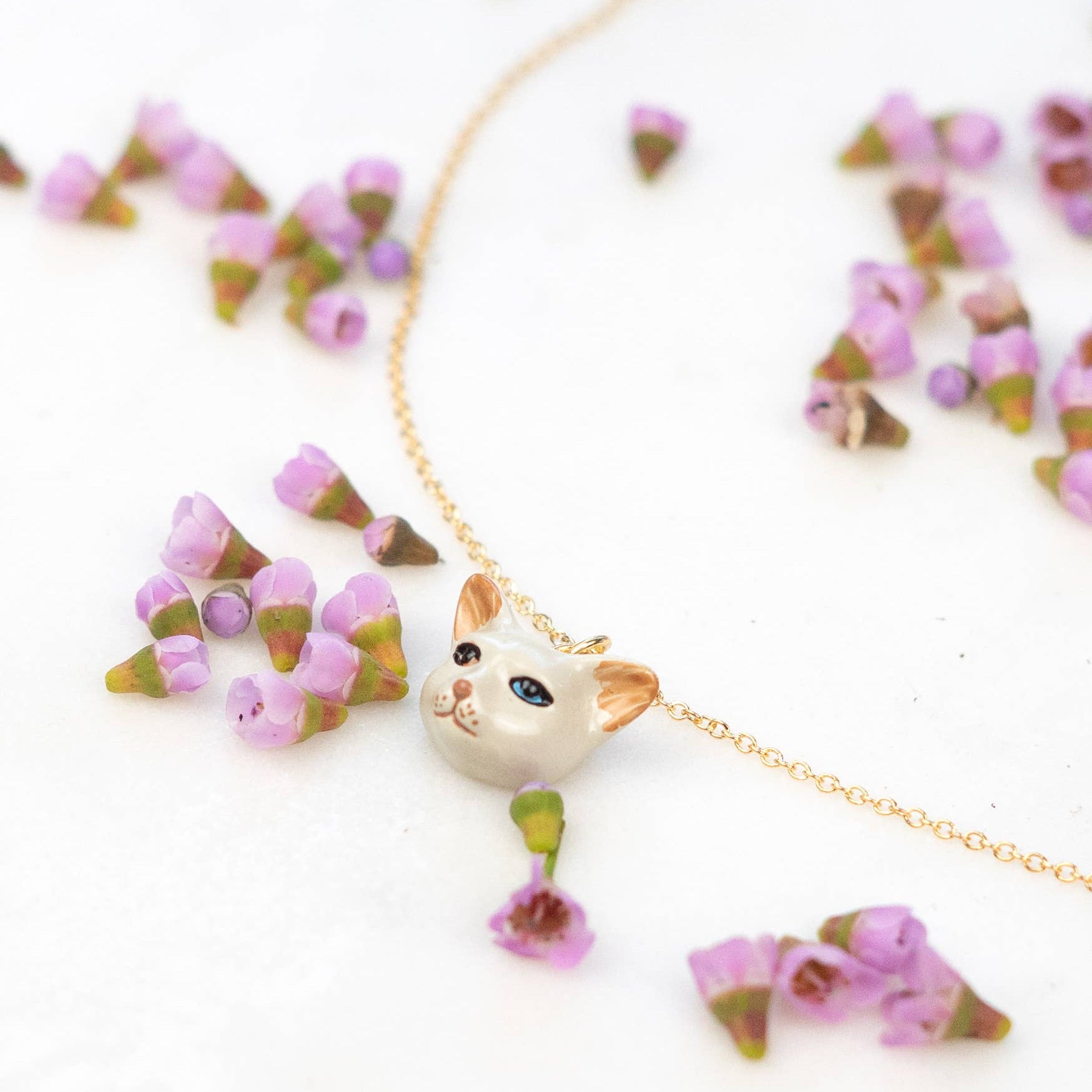 Necklace with a cat-shaped pendant and floral elements on a white background