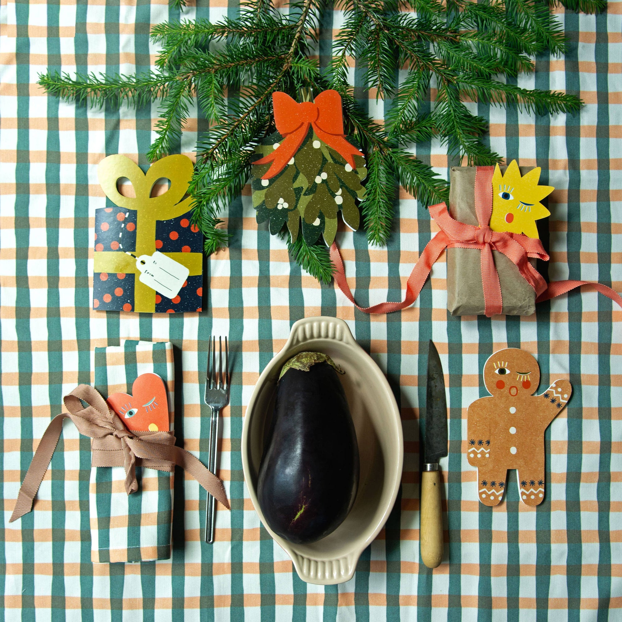 Decorative table setting with Christmas-themed ornaments on a striped tablecloth.