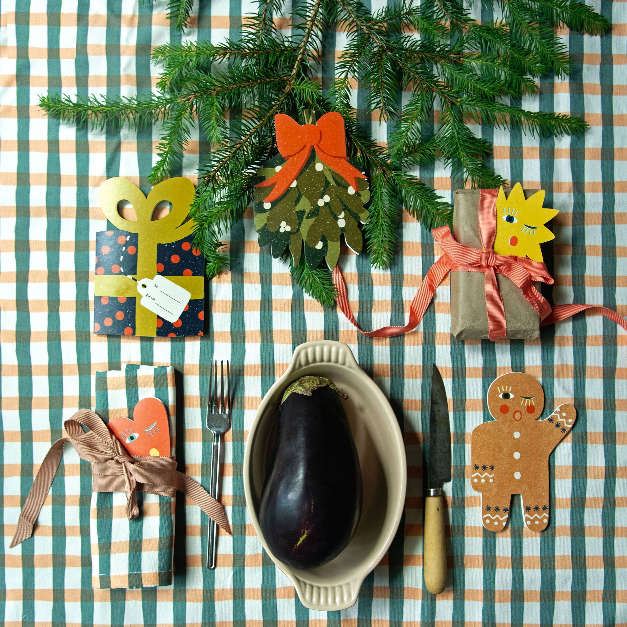 Decorative table setting with Christmas-themed ornaments on a striped tablecloth.