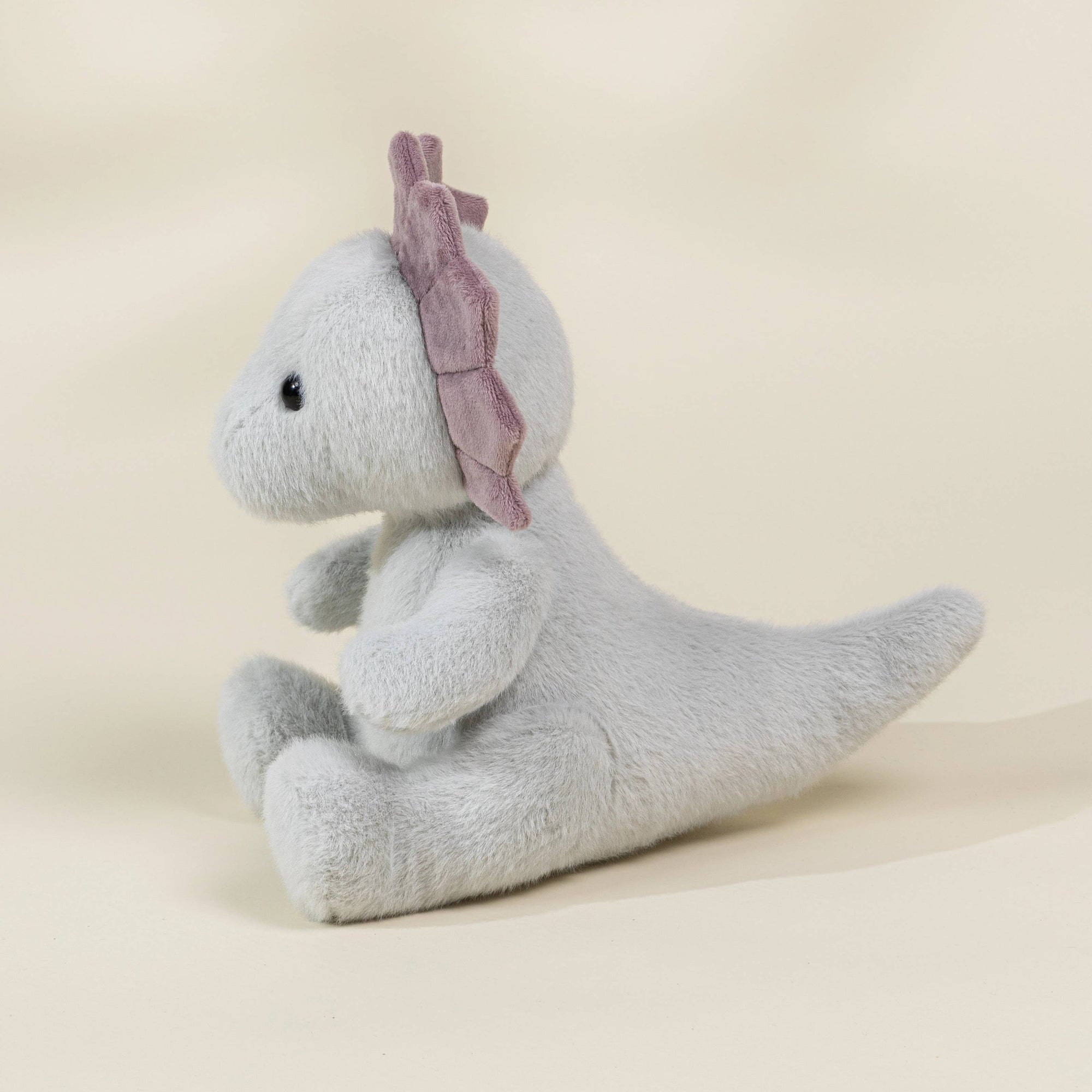 Gray plush dino on a beige background