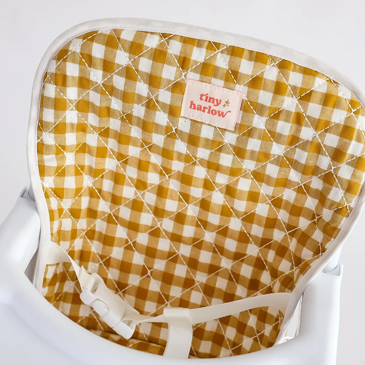 Yellow and white checkered chair pad with 'tiny harlow' brand on a white background