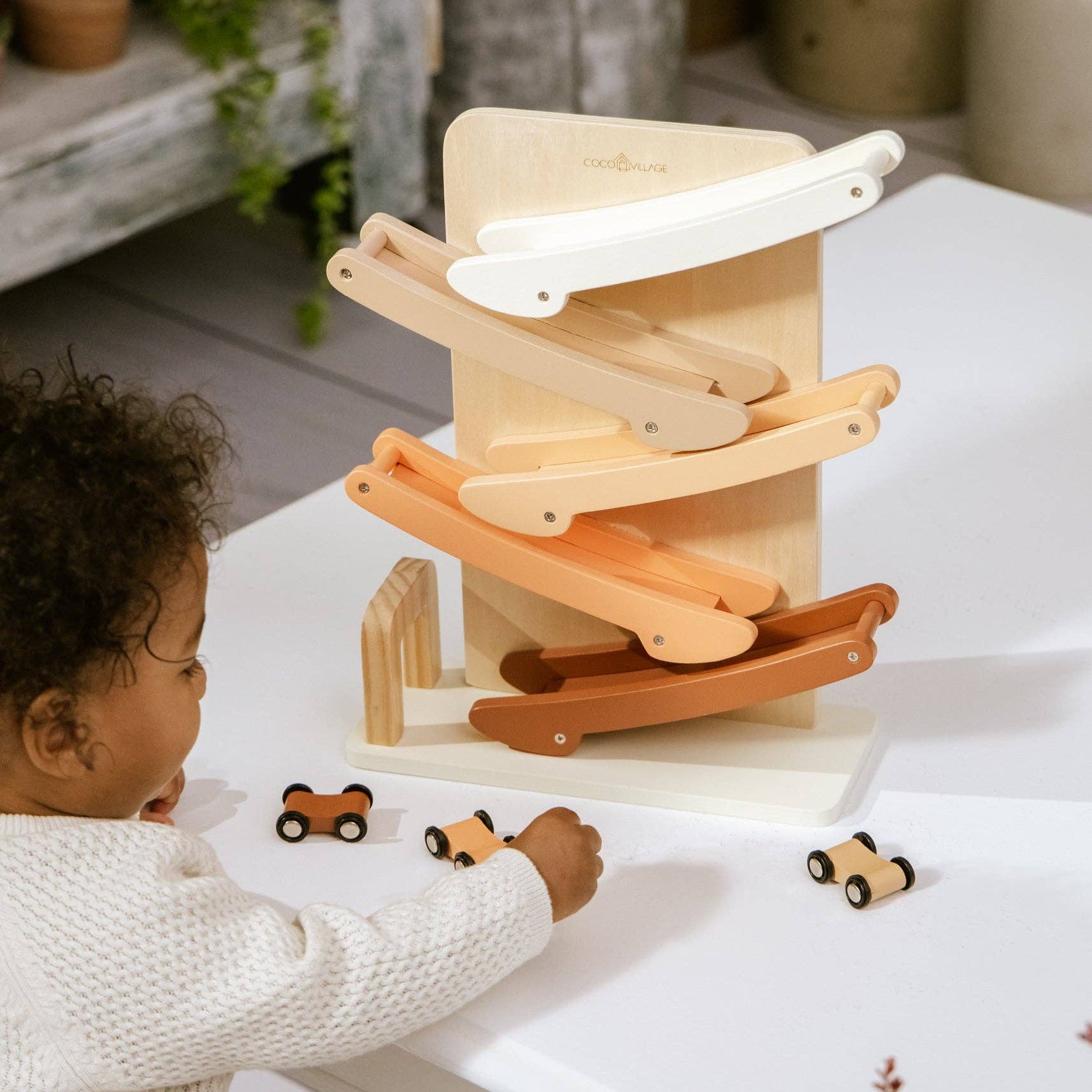 Child playing with a wooden toy set on a white surface.