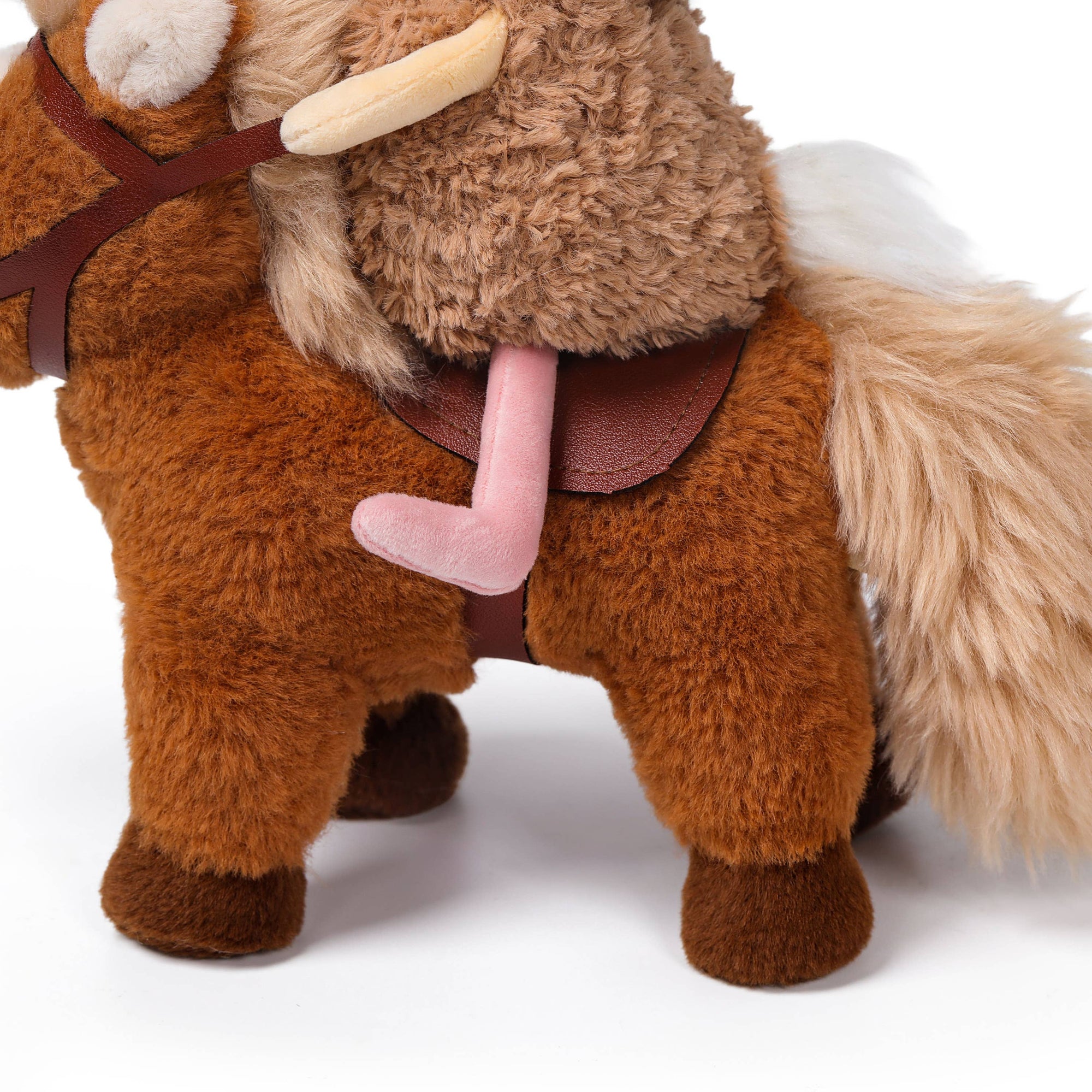 A plush toy mule or donkey with brown and tan fur, a pink saddle, and a white tail, photographed on a clean white background.