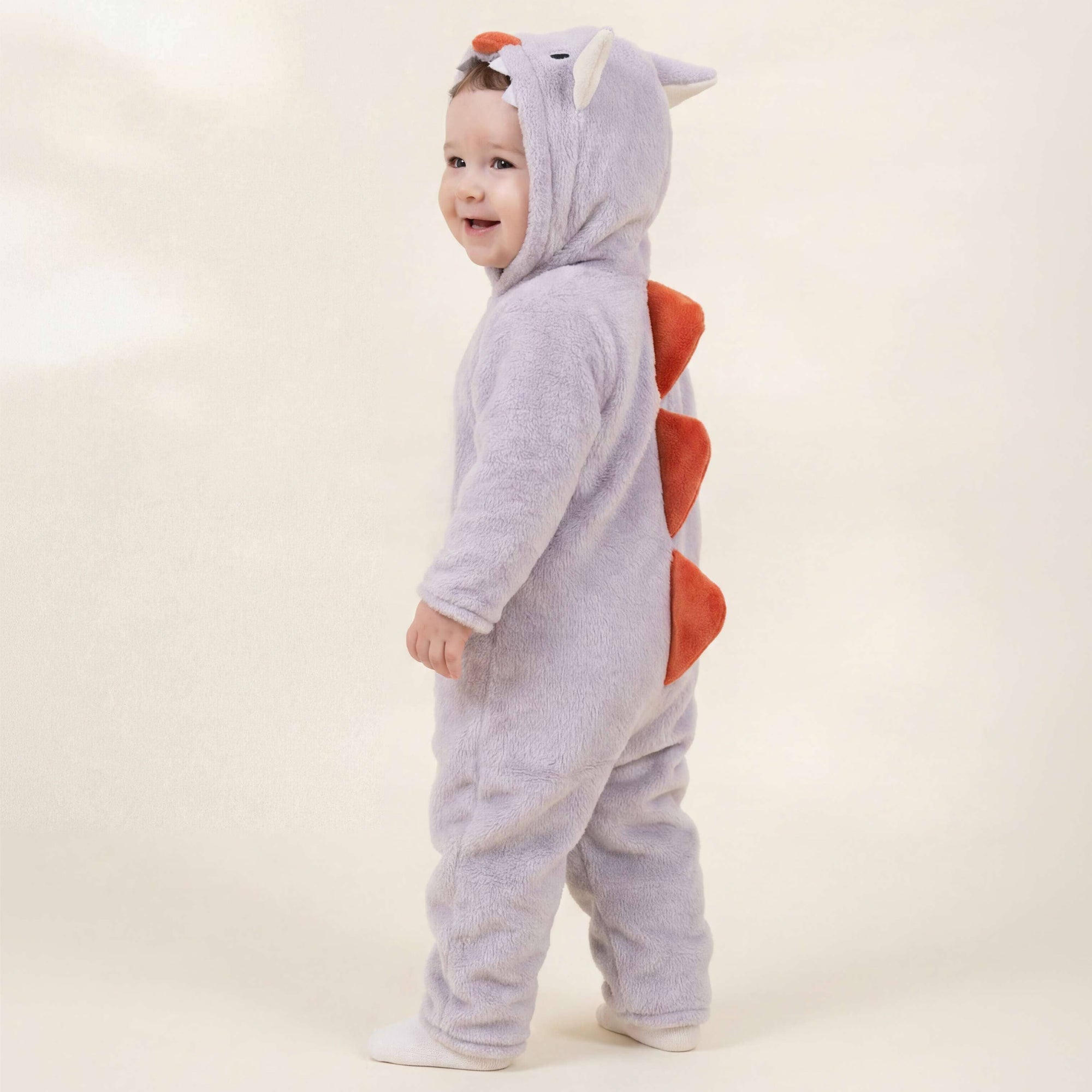 Child wearing a gray dinosaur onesie with red accents on a white background