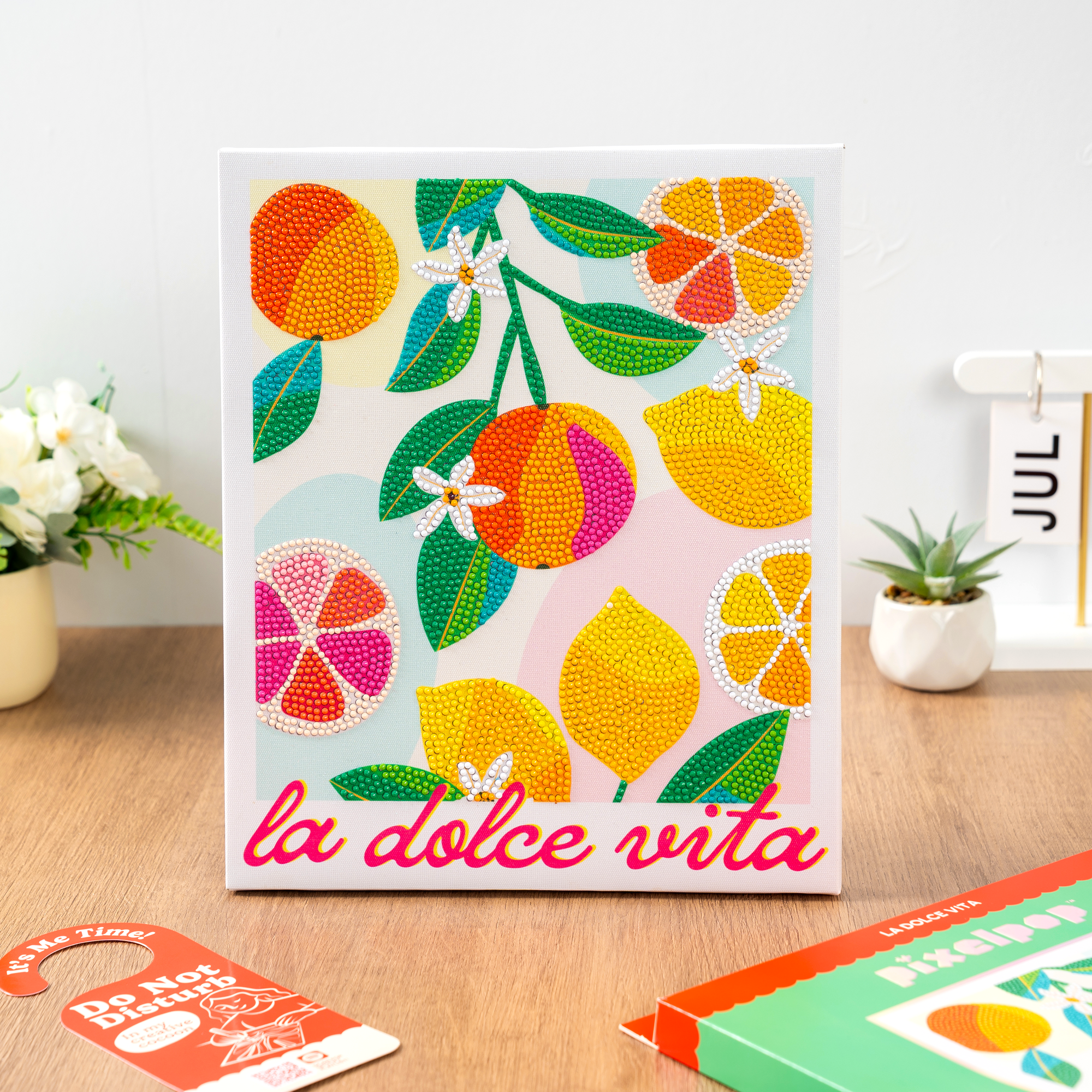 Colorful card with citrus fruits and 'la dolce vita' text on a wooden surface.