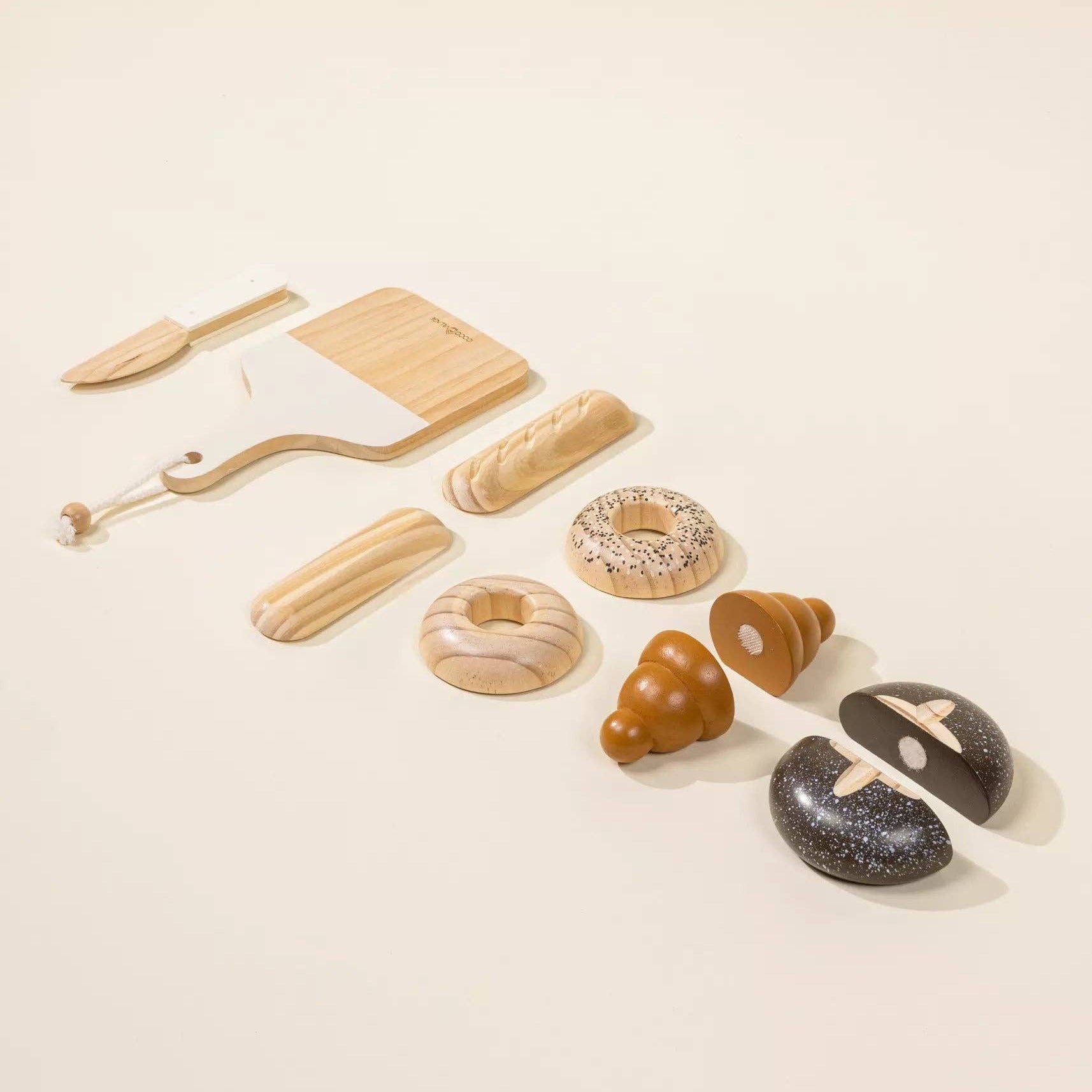 Set of toy bread and baking tools on a beige background