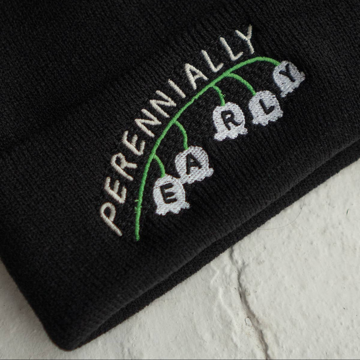 Black beanie with embroidered text on a light gray background