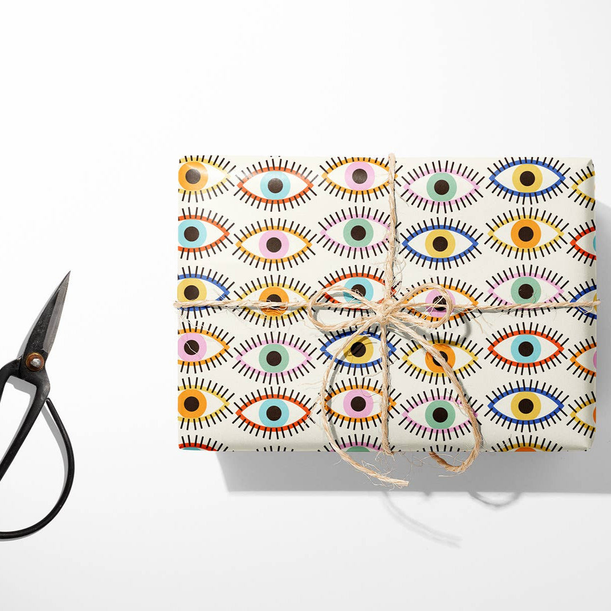Gift wrapped in colorful patterned paper with scissors and twine on a white background