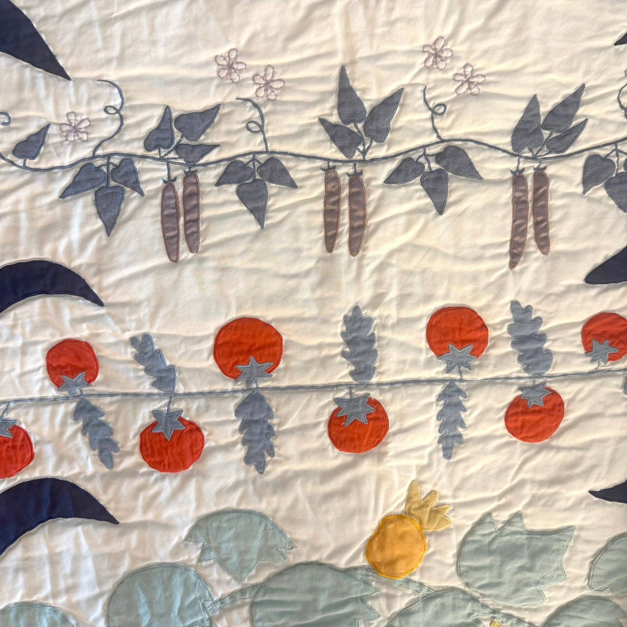 Quilt with floral and vine patterns on a light background