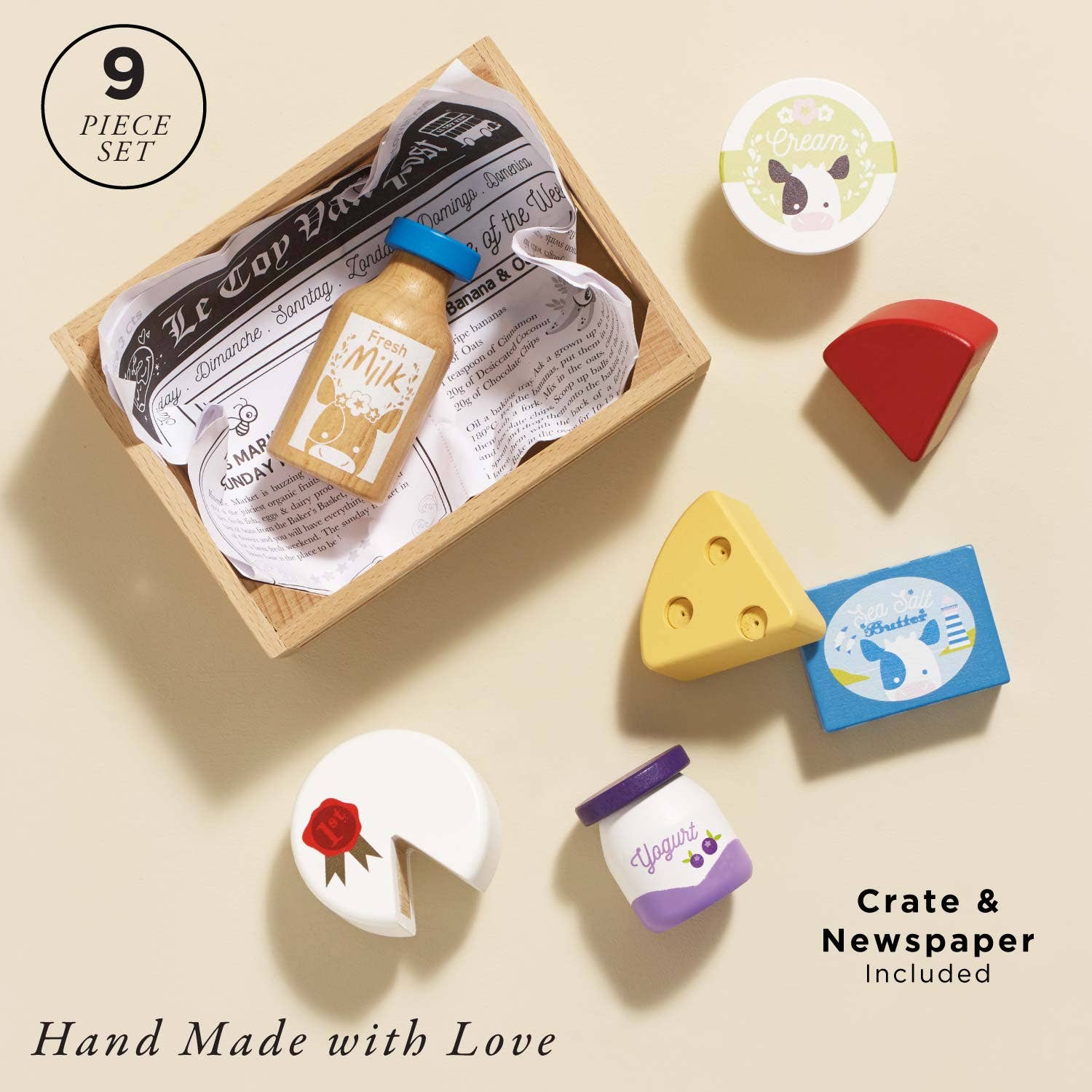 Set of hand-made cheese and milk-themed rubber stamps with a wooden crate and newspaper included on a beige background.