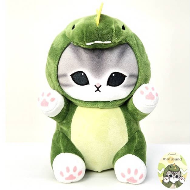 Plush toy of a cat in a green dinosaur costume on a white background