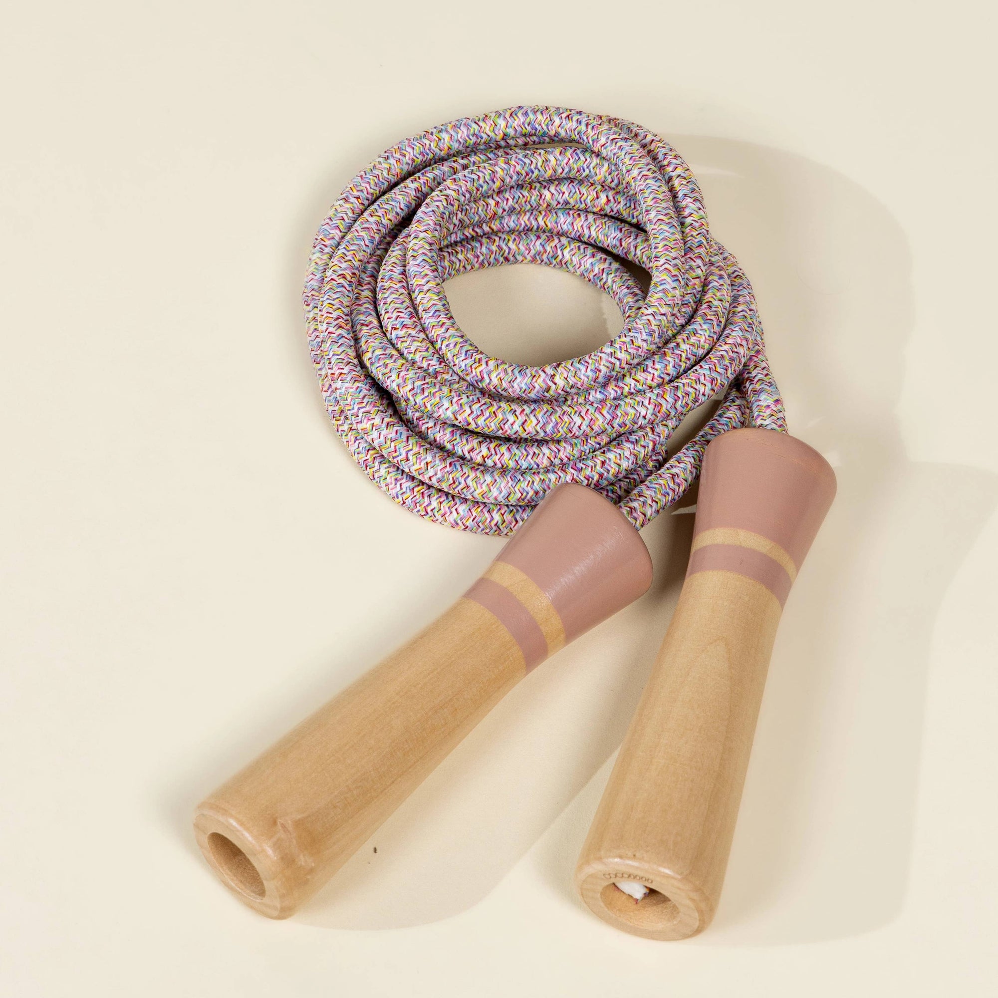Coiled jump rope with wooden handles on a beige background