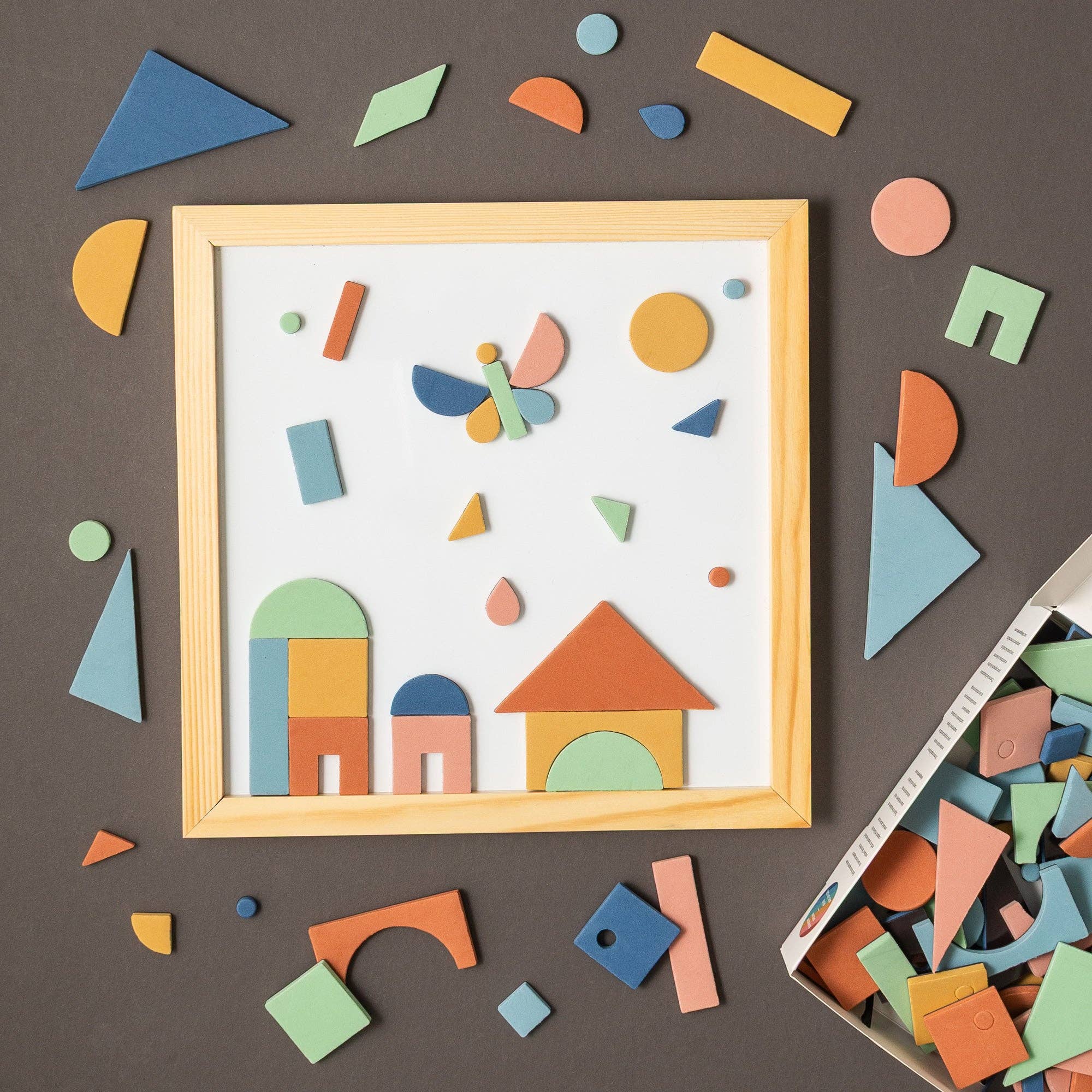 Framed children's art with colorful geometric shapes on a brown background