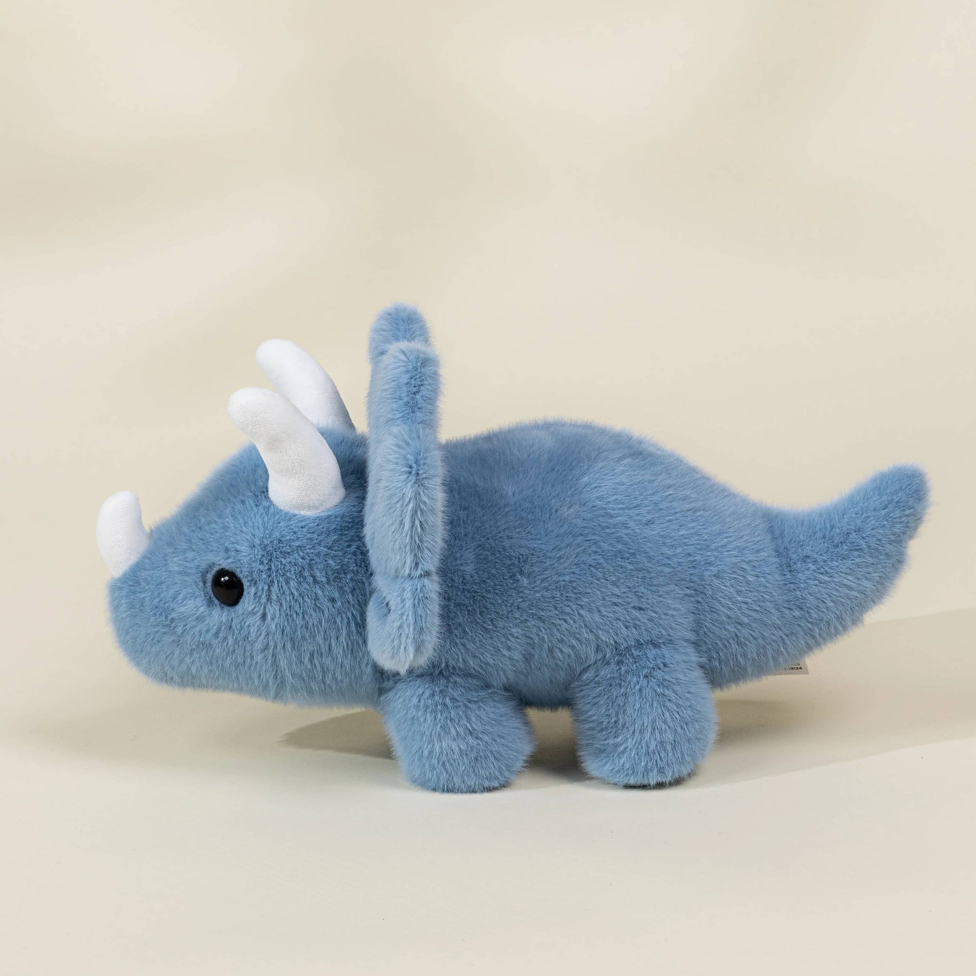 Blue plush triceratops toy on a beige background