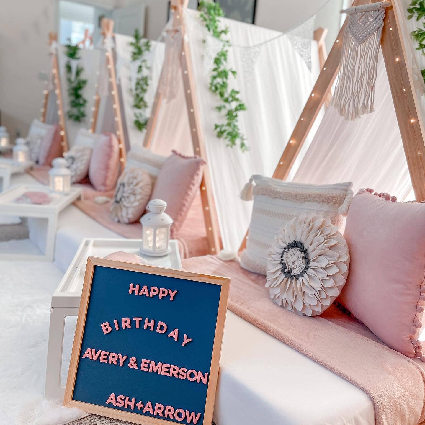 Decorative setup with pillows, lanterns, and a 'Happy Birthday' sign in a cozy indoor setting.