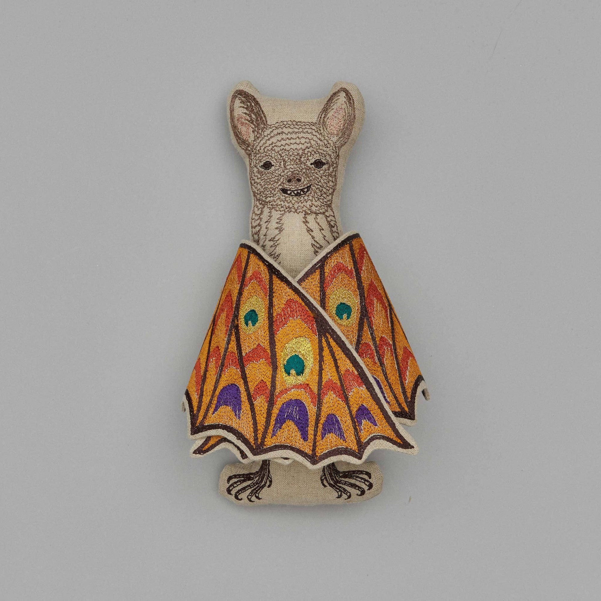 Decorative brooch with a bat design wearing a colorful batwing dress on a gray background