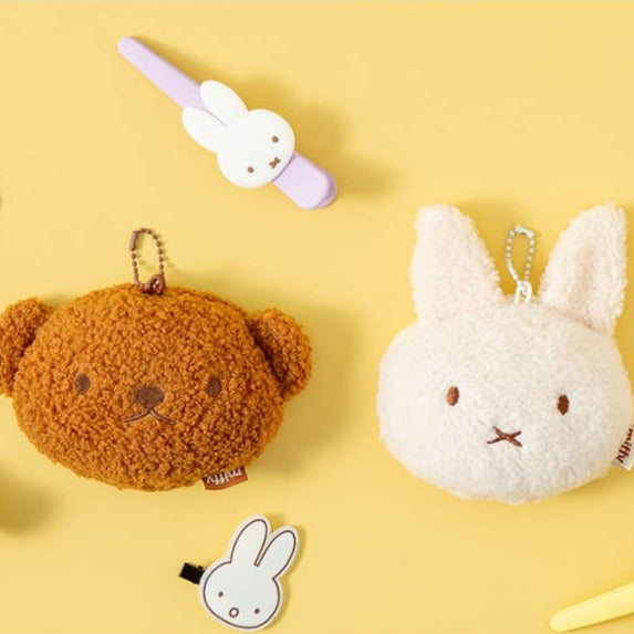 Plush keychains including a brown bear and white rabbit on a yellow background