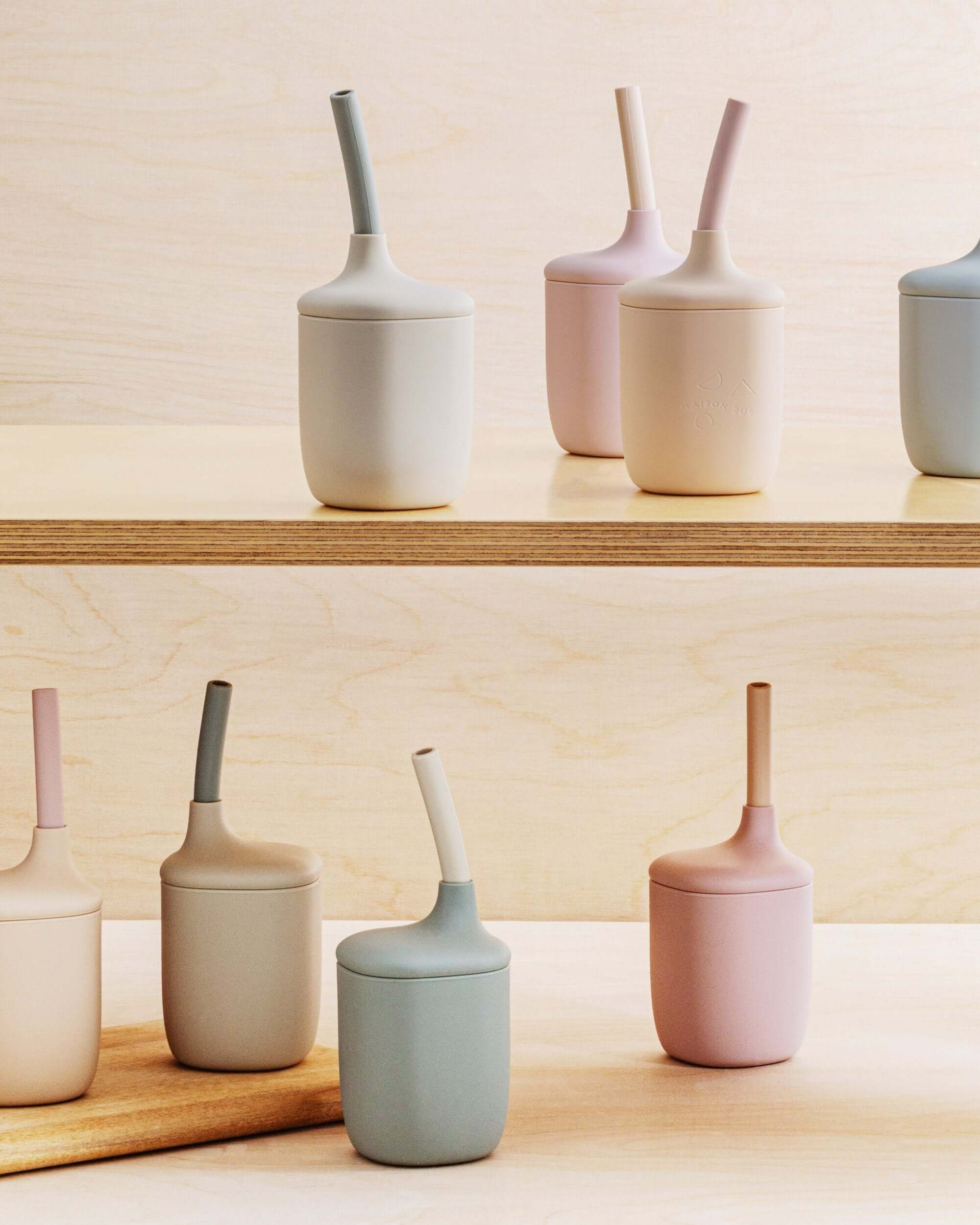 Set of silicone cups with handles on a wooden surface and light-colored wall background