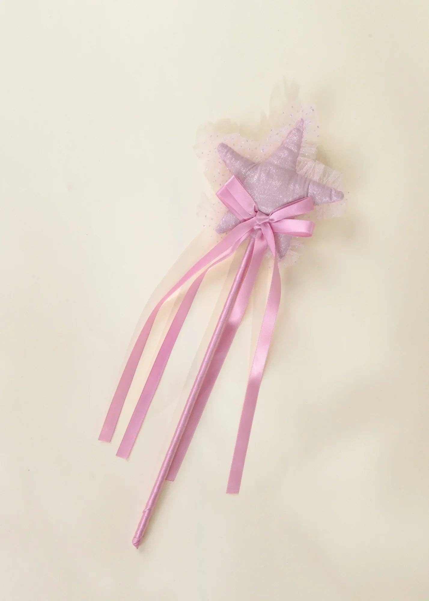A pink and lavender star-shaped wand with a lace-topped star, pink satin ribbon bow, and long pink ribbon tails, shown on a plain cream background.