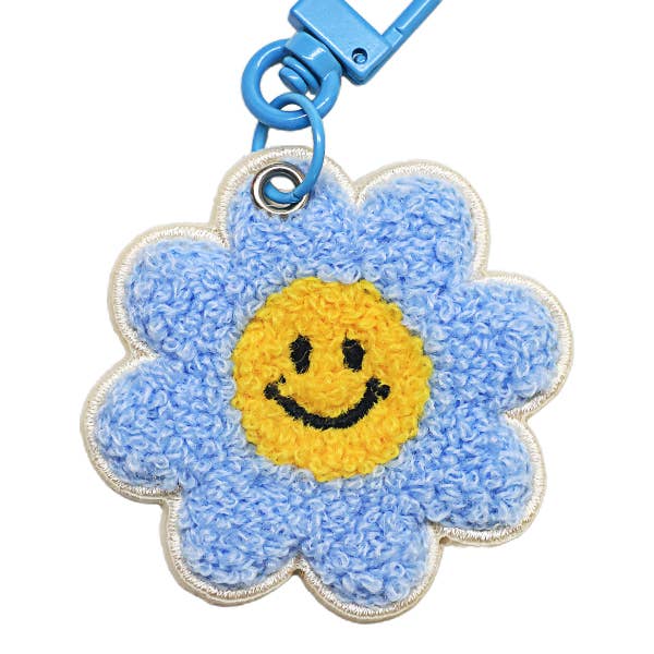 Blue flower-shaped keychain with a yellow center and smiley face on a white background