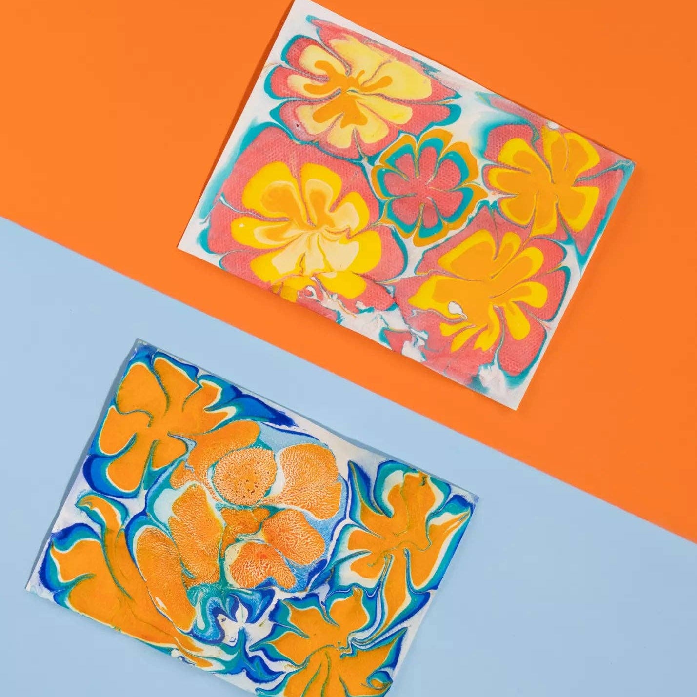 Two colorful floral glass coasters on a blue and orange background