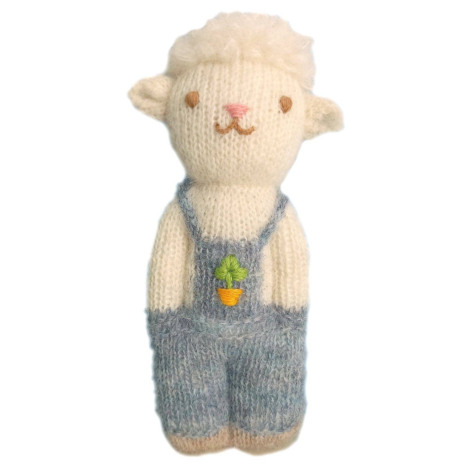 Knitted toy sheep wearing overalls on a white background