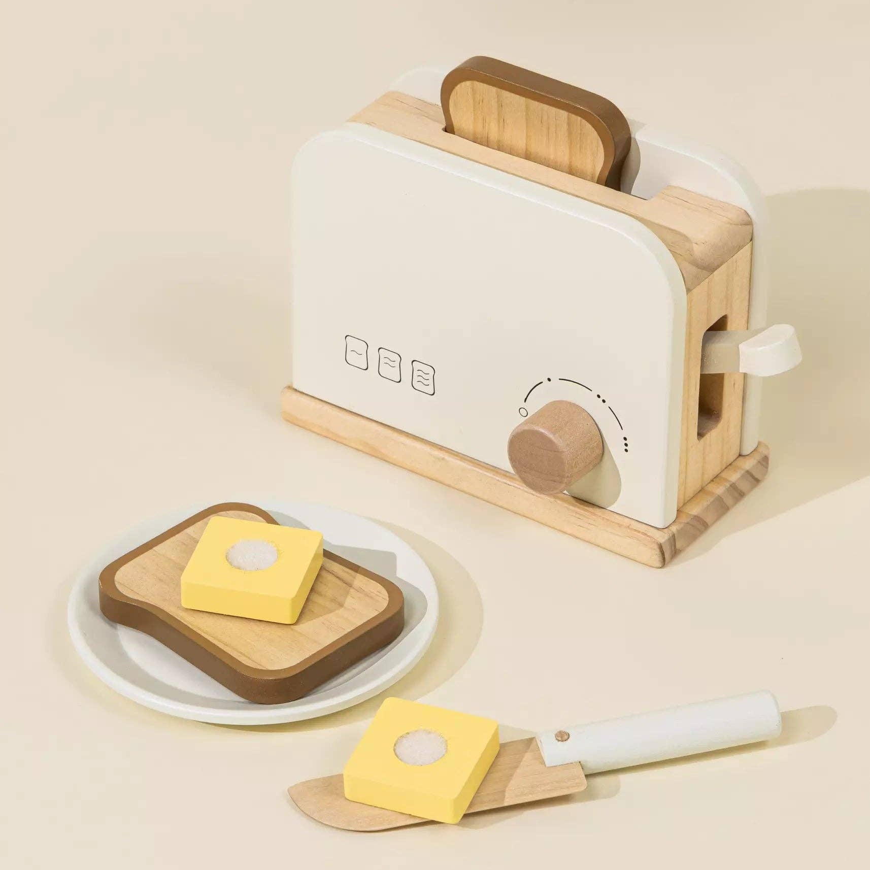 Toy toaster with bread and butter on a beige background