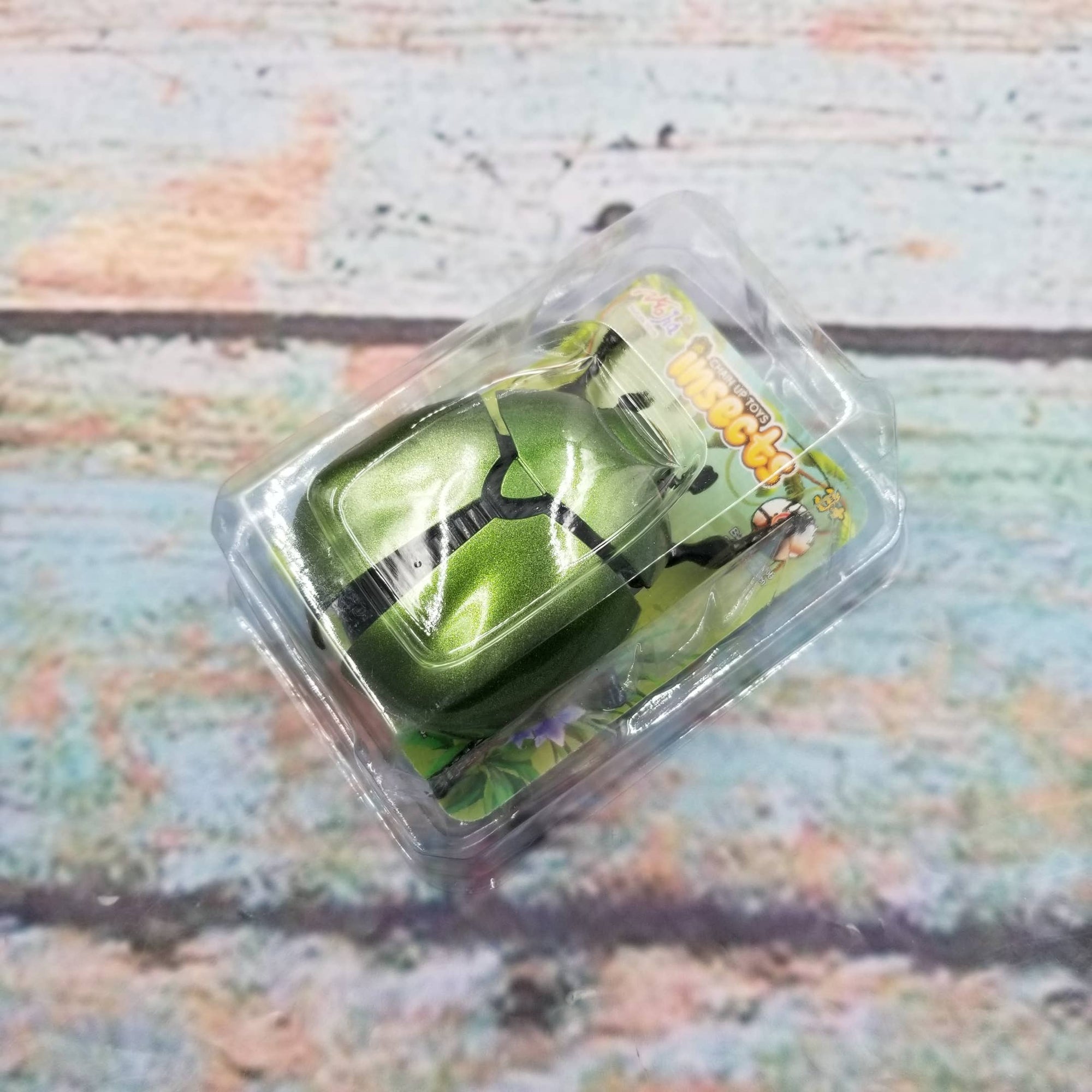Green toy car in clear packaging on a textured surface