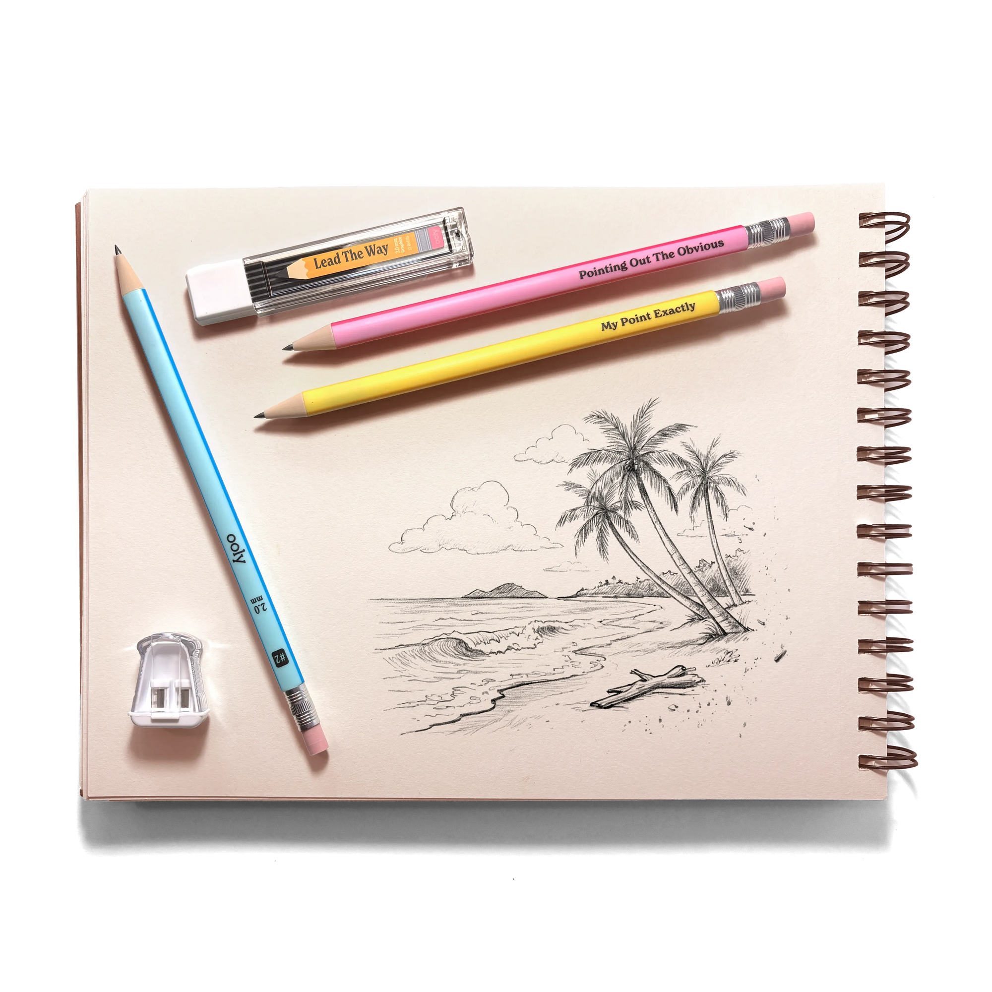 Notebook with a beach scene drawing, colored pencils, and an eraser on a white background
