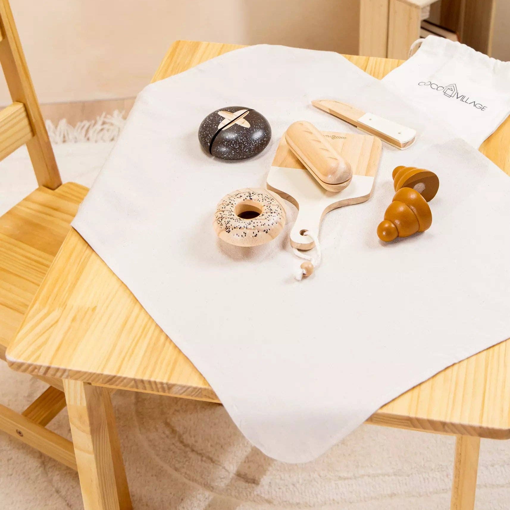 Wooden table with a white cloth, decorative items, and a sheep plush toy on a wooden stool.