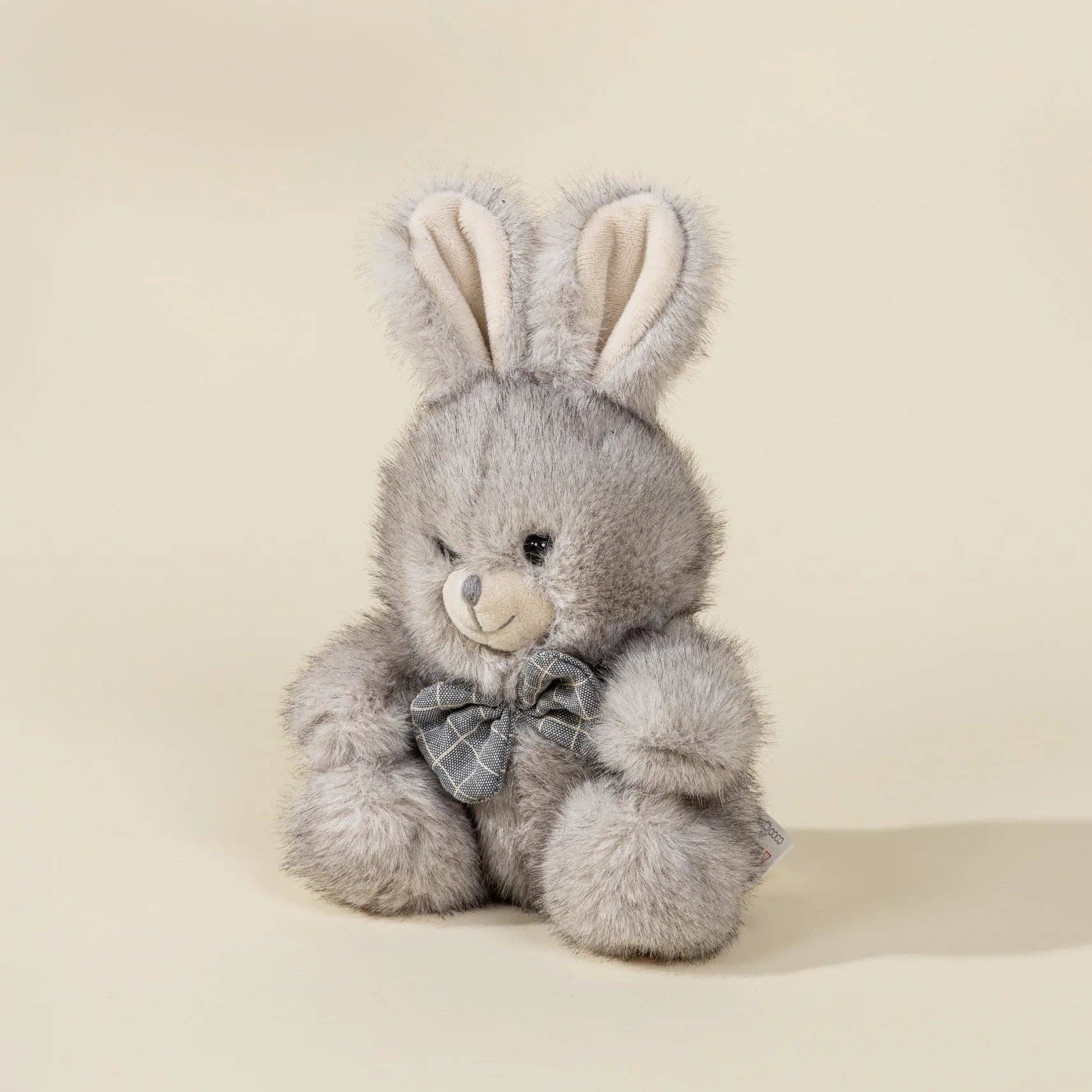 Gray plush bunny with a bow tie on a beige background