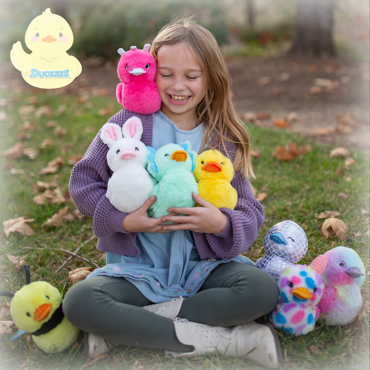 Girl holding plush toys outdoors with a duckling plush toy in the corner.