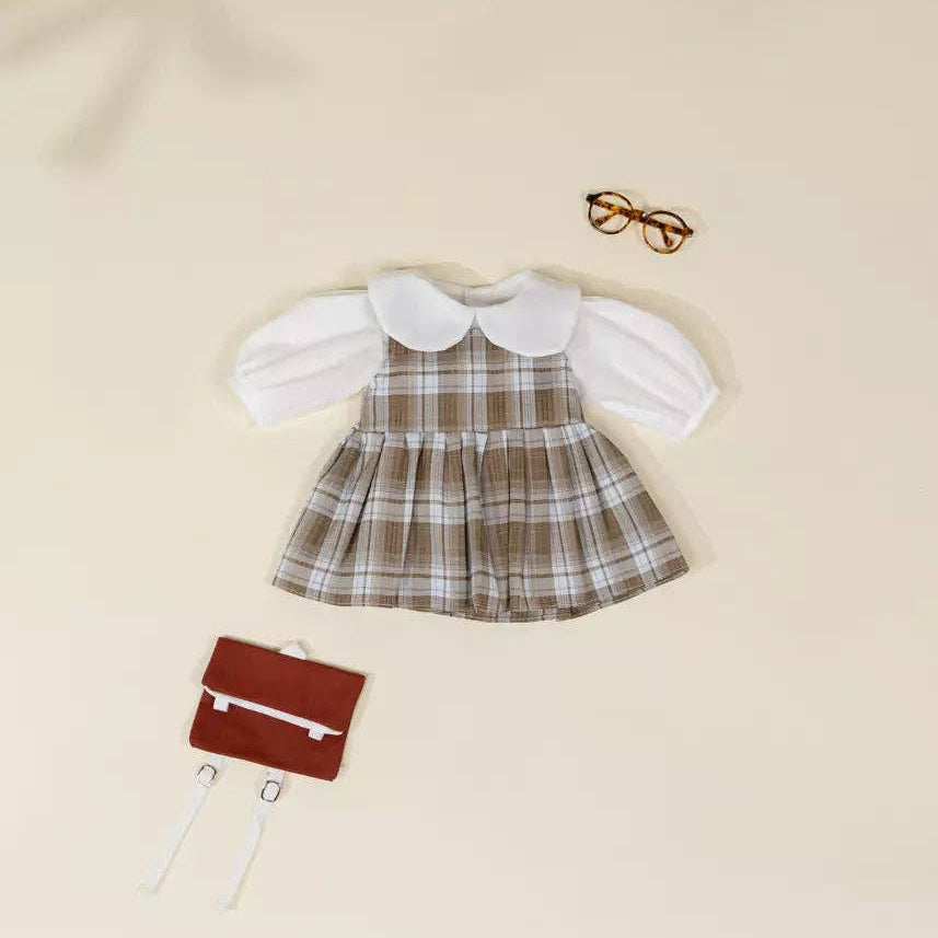 Plaid dress with white blouse, red bag, and glasses on a beige background