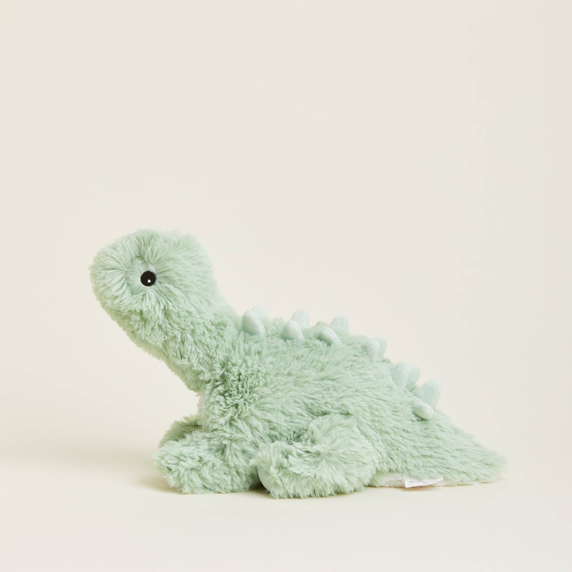 Plush dinosaur toy in light green on a beige background