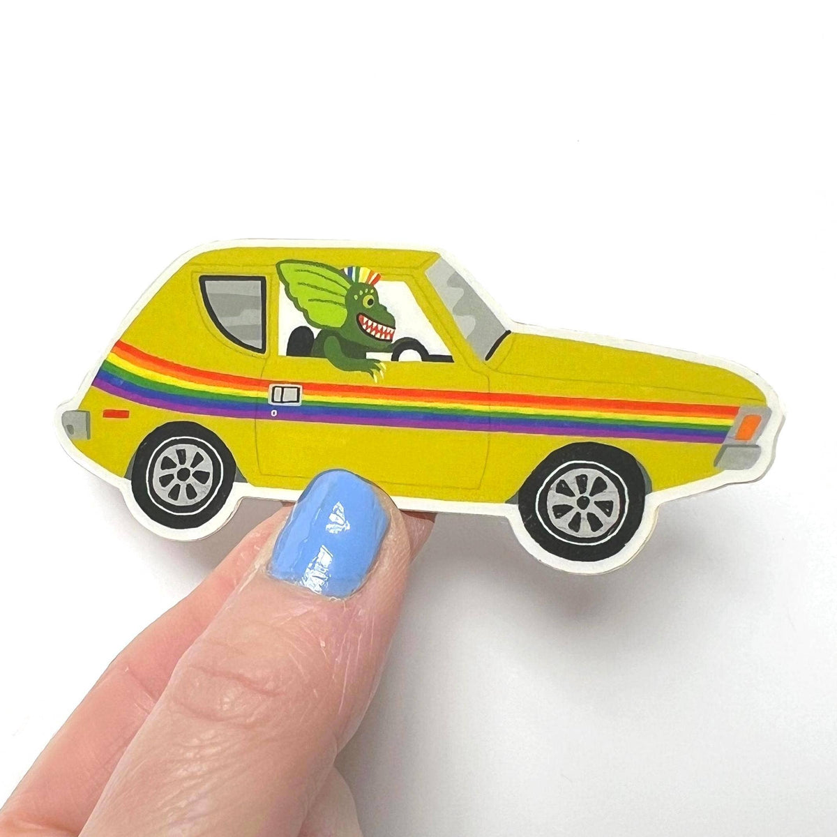 Yellow car-shaped object with rainbow stripes held by a hand on a white background