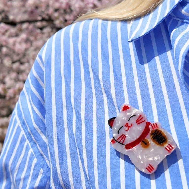 Person wearing a blue and white striped shirt with a cat-shaped brooch.